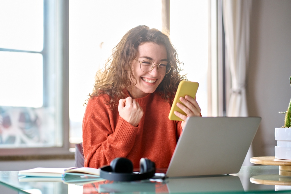 A woman is looking at her phone, showcasing a moment of happiness.
